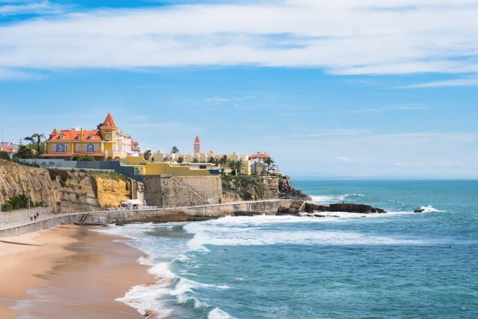 Beautiful view of Cascais Bay, with a sandy beach in the background and a cliff overlooking the blue ocean.