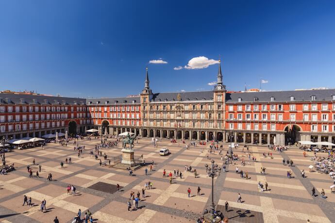 Plaza Mayor in Madrid, Spain, a historic central square surrounded by elegant red-brick buildings and lively city life