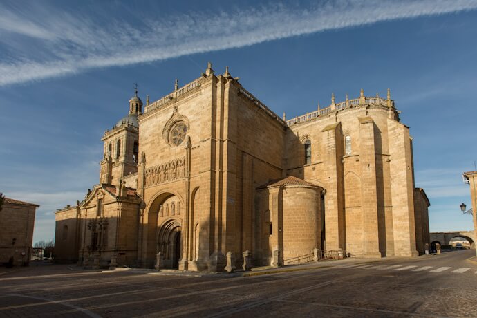 Historic cathedral in Ciudad Rodrigo, Spain, with its Romanesque and Gothic stone façade under a clear blue sky.