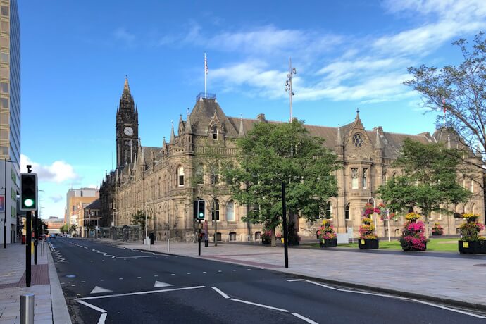 Street view of Middlesbrough Town Hall and civic buildings with flower displays and clear blue skies.