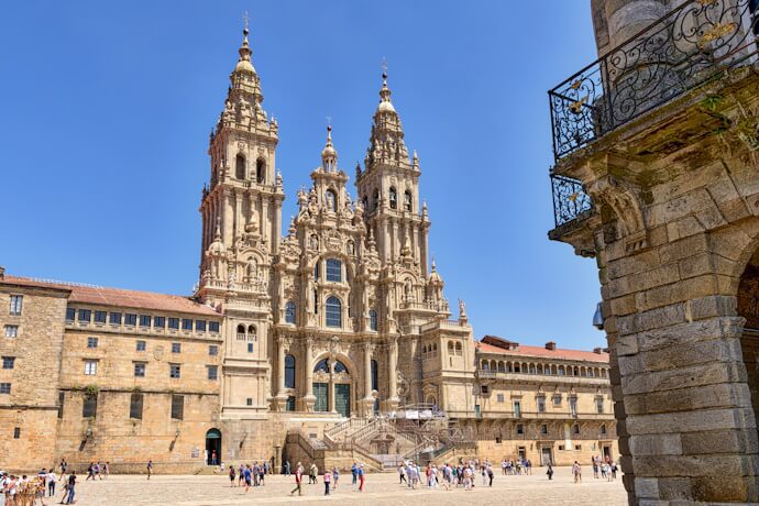 Iconic baroque façade of Santiago de Compostela Cathedral in Galicia, Spain, with visitors gathered in the square below.