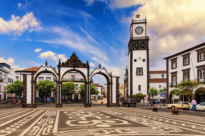 Ponta Delgada city center in São Miguel, Azores, with the Portas da Cidade, patterned cobblestone square, and historic clock tower.