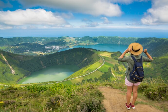 View over Sete Cidades crater lakes in São Miguel, Azores, with a traveler overlooking the volcanic landscape.