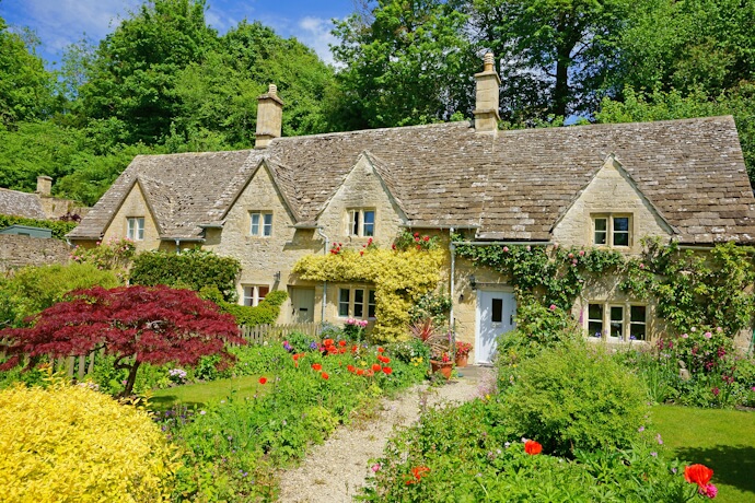 Traditional Cotswolds cottage with colorful garden in bloom.