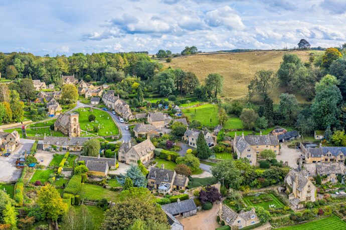 Aerial view of a Cotswolds village set among rolling hills.