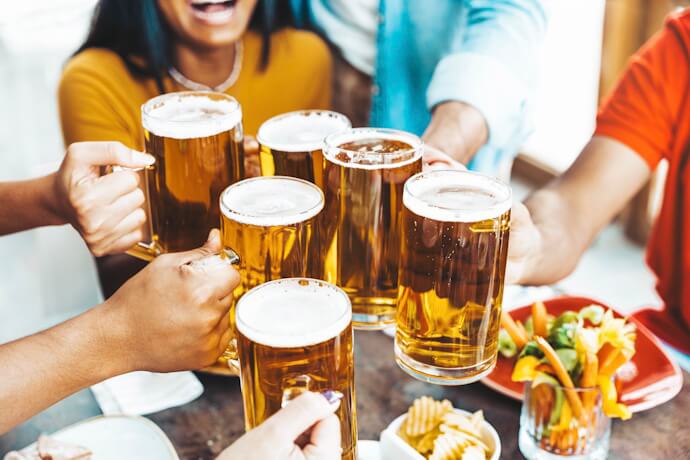 Group of happy people cheering with beer at brewery pub restaurant