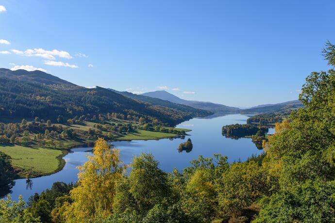 A breathtaking view over Loch Tummel, showcasing the serene beauty of the Scottish Highlands under a crisp blue sky.