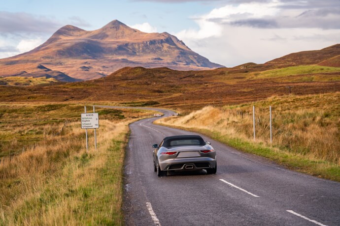 A winding road leads into the heart of the Highlands, with golden moors and majestic mountains setting the scene for a breathtaking road trip.