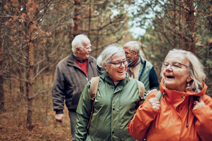 A joyful group of seniors exploring a peaceful woodland trail, embracing the natural beauty and camaraderie of the Scottish outdoors.