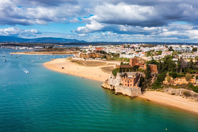 Ferragudo and Praia da Angrinha in the Algarve, with golden sandy beach, calm blue waters, and whitewashed houses along the coastline