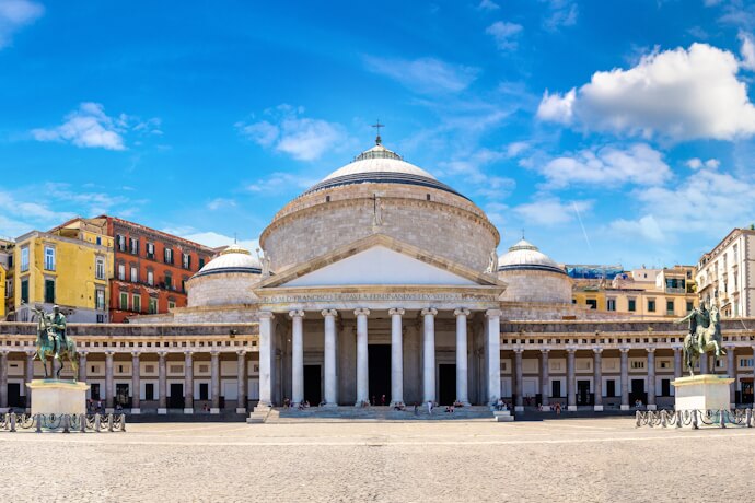 Sunlit view of the Basilica of San Francesco di Paola and its grand colonnade in Piazza del Plebiscito in Naples, Italy.