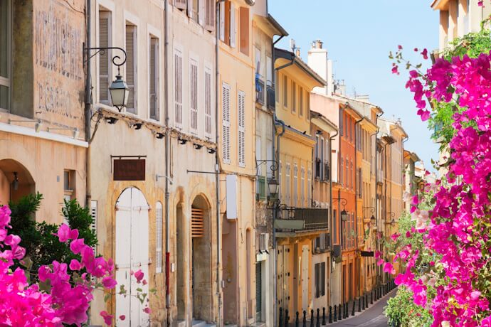 Charming Provençal street lined with pastel houses and blooming bougainvillea in southern France.