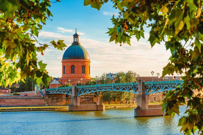 Scenic view of Toulouse with its iconic domed church and bridge over the Garonne River.