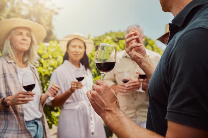 Wine tasting experience in a vineyard, with guests sampling red wine in a relaxed outdoor setting.
