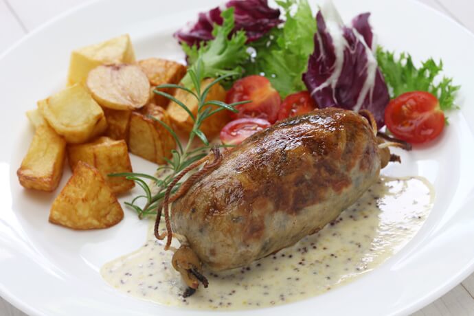 Classic French dish featuring sausage with potatoes and salad, showcasing regional cuisine.