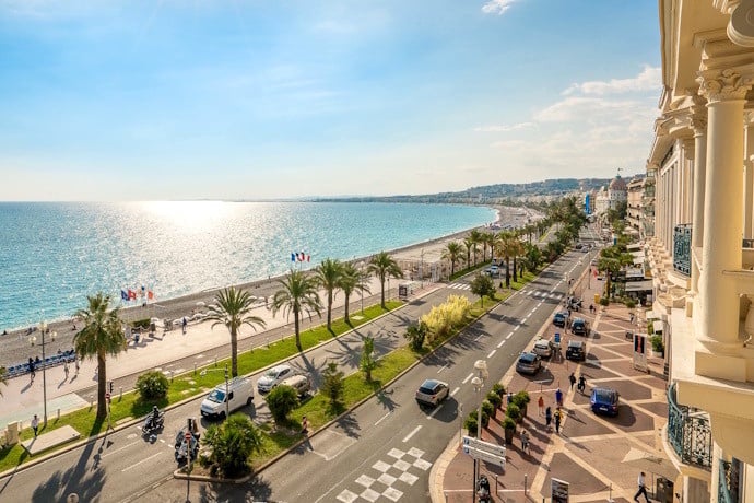 Promenade des Anglais in Nice, France, with palm-lined seafront boulevard, Mediterranean coastline, and vibrant city life