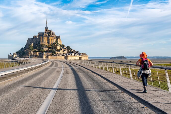 Woman walking towards the UNESCO-listed Mont-Saint-Michel in Normandy, France