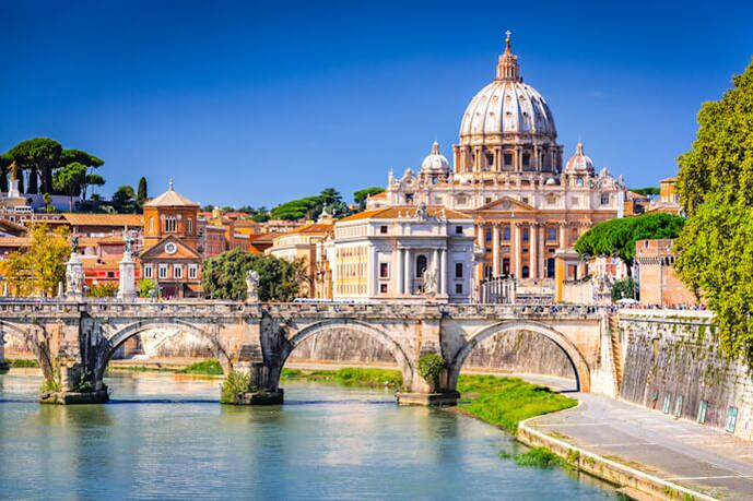 People visiting Saint Peter Basilica and crossing Sant'Angelo Bridge on a sunny day. 