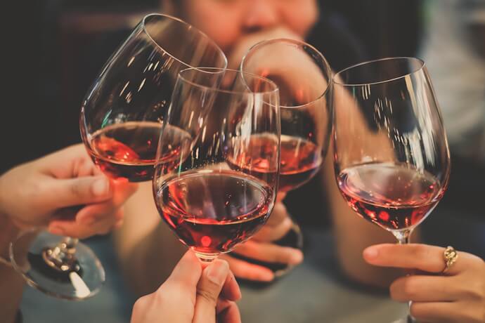 Friends raising glasses of red wine in a cheerful toast at a bar or restaurant.