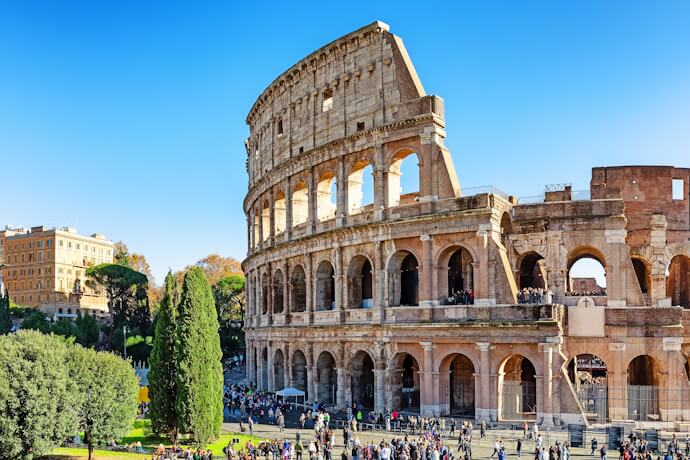 The Colosseum in Rome with visitors on a sunny day.