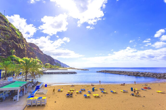 Golden sandy beach in Calheta, Madeira, with sun loungers and sheltered blue waters