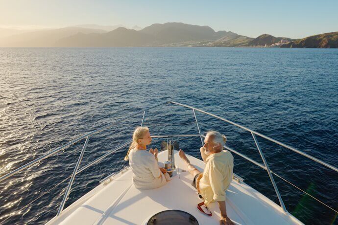 Two people relaxing on a boat enjoying the Atlantic Ocean and coastal scenery of Madeira, Portugal
