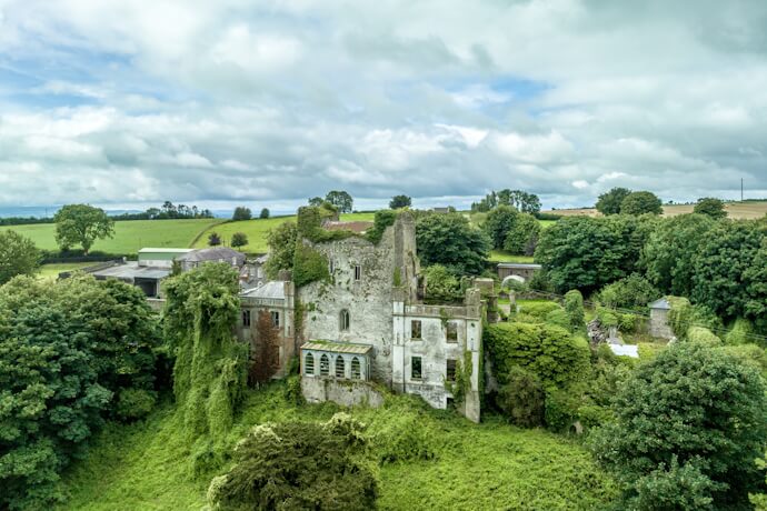 Ivy-covered ruins of Leap Castle surrounded by green countryside in County Offaly, Ireland.