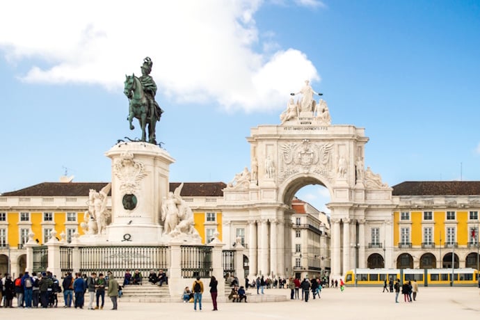 Praça do Comércio in Lisbon, Portugal, featuring the bronze statue of King José I and the ornate Arco da Rua Augusta with classic yellow Pombaline buildings.