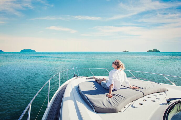 Luxury yacht cruising on calm turquoise waters with a traveler relaxing on the deck