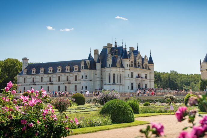 Château de Chenonceau in the Loire Valley surrounded by formal gardens and visitors exploring the grounds.