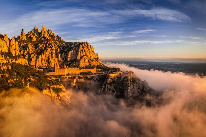 Montserrat monastery perched on rocky peaks above clouds in Catalonia