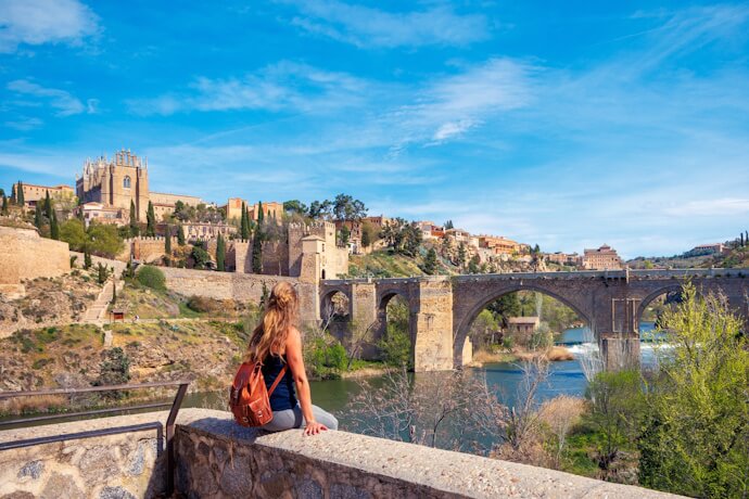 View of Toledo’s historic skyline and bridge over the Tagus River with a visitor in the foreground