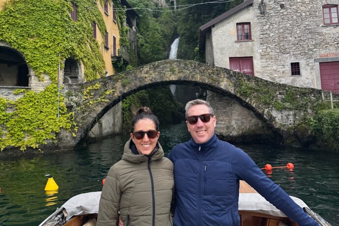 Couple enjoying a boat tour past the picturesque Ponte della Civera in Nesso, Lake Como, Italy