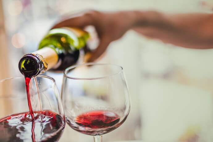Italian red wine being poured from a bottle into two glasses