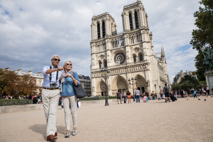 A senior couple walking in front of Notre-Dame Cathedral in Paris