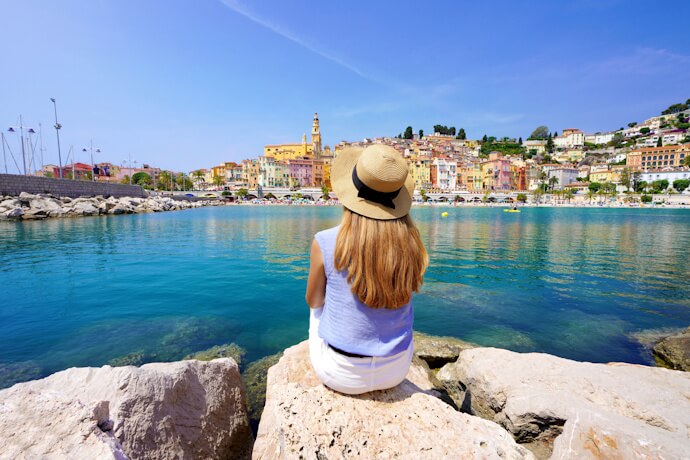 Woman overlooking colorful seaside town of Menton, France, on sunny day