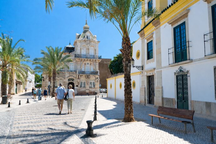 Palm-lined street and historic architecture in Faro Old Town, Algarve.