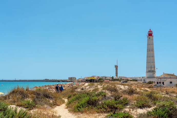 Coastal path and lighthouse at Ilha do Farol, Ria Formosa Natural Park, Algarve.