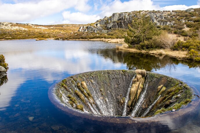 Covão dos Conchos, the distinctive bell-mouth spillway in a mountain lagoon in Serra da Estrela.