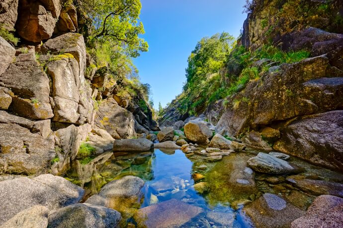 Clear mountain stream flowing between granite cliffs and boulders in Peneda-Gerês National Park.