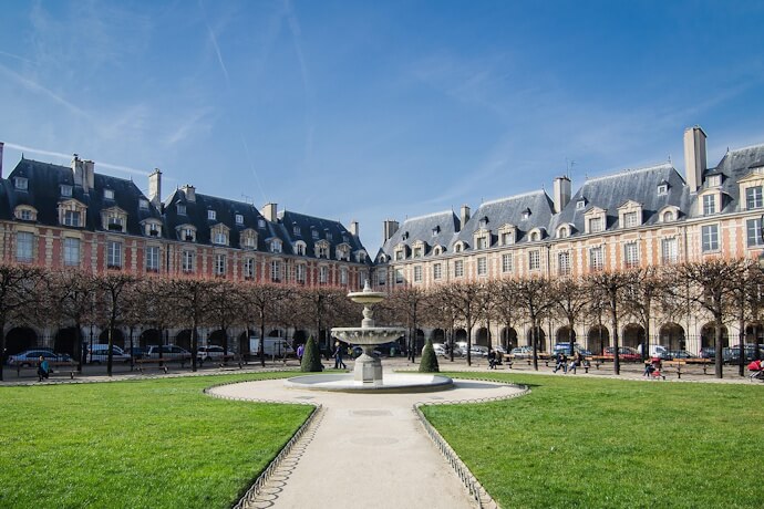 People enjoying the sun in Place des Vosges, Marais, Paris