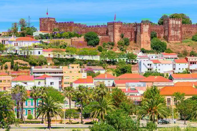 Silves Castle rising above the town’s whitewashed houses and palm-lined streets in the Algarve, Portugal.