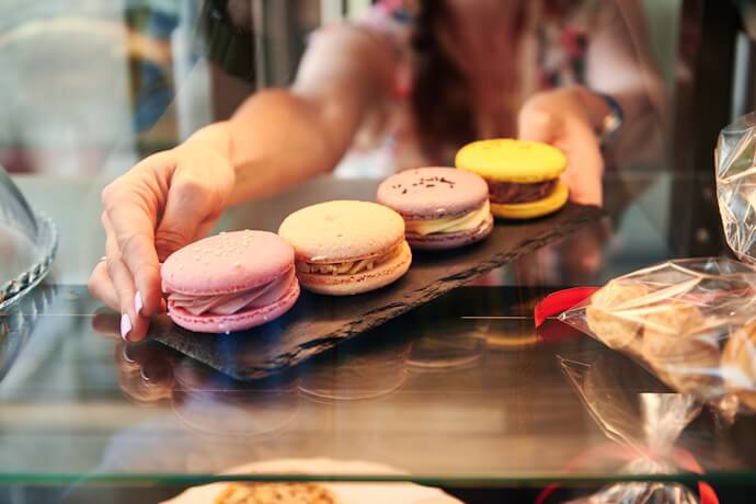 Colorful macarons on a plate, surrounded by white blossoms.