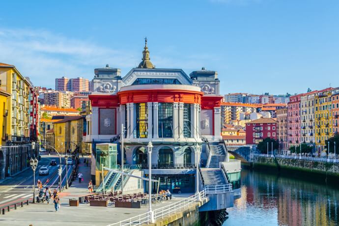 Exterior of Mercado de la Ribera in Bilbao, Spain, featuring its Art Deco façade and riverside location along the Nervión River