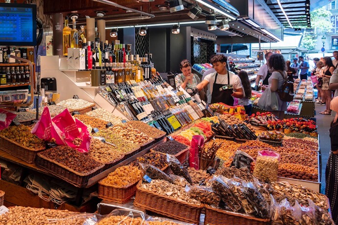 nterior of La Boqueria Market in Barcelona, Spain, bustling with people browsing colorful food stalls