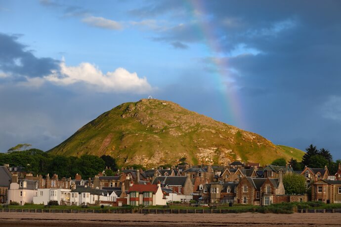 North Berwick Law rising above the coastal town beneath a rainbow, Scotland.