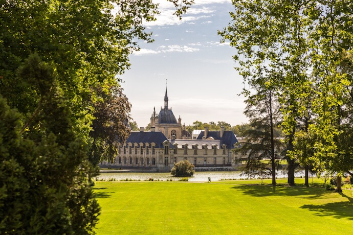 Scenic view of the Château de Chantilly surrounded by lush gardens, near Paris, France