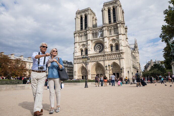 Senior couple walking in front of the iconic Notre-Dame Cathedral in Paris