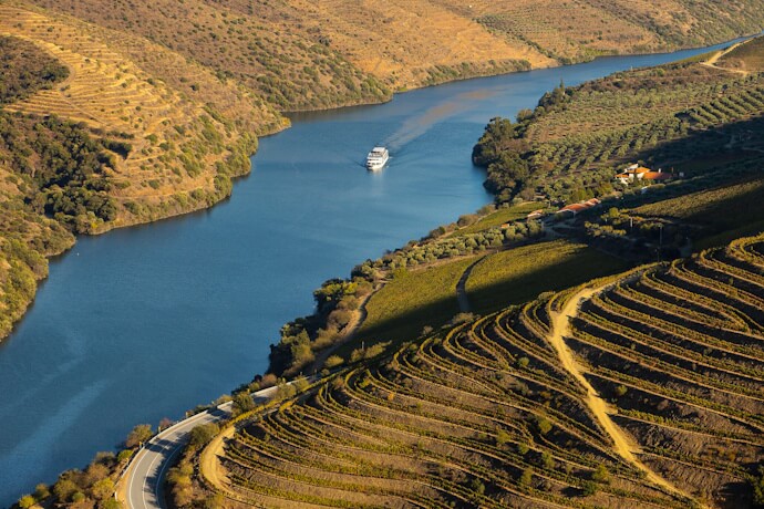 Aerial view of the vinyard-covered Douro Valley and a boat crossing the river
