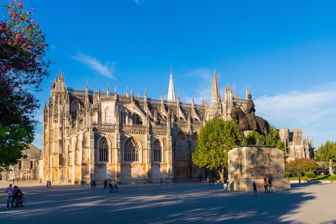 View of people passing by Batalha Monastery with equestrian statue in Portugal